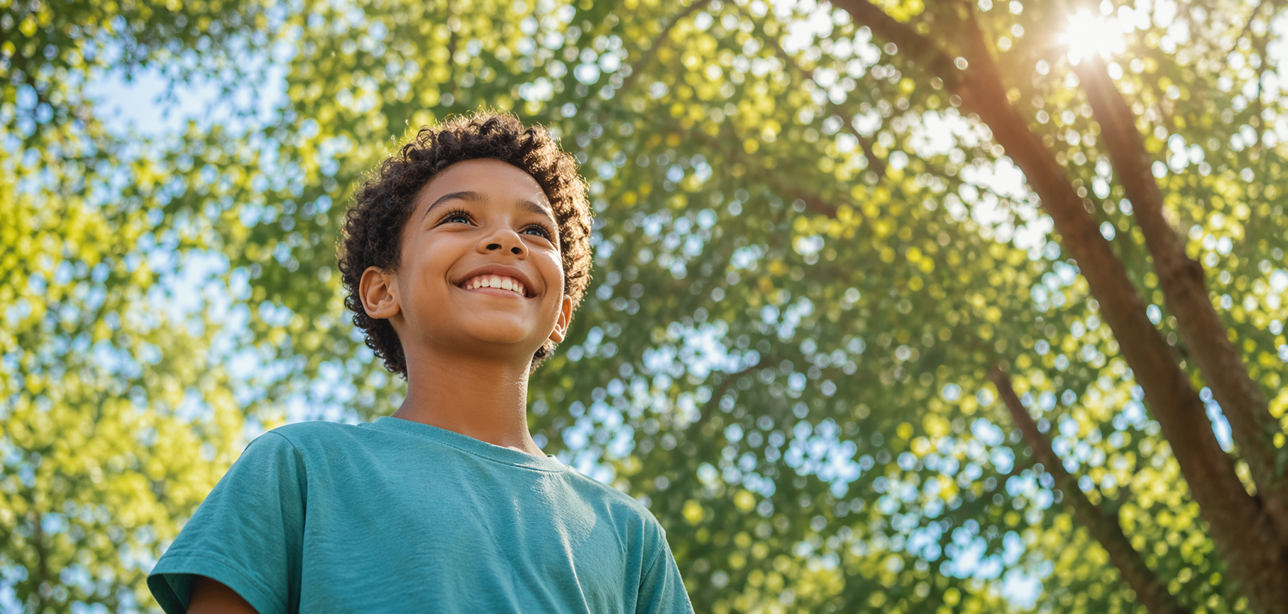 A smiling child under trees and warm sunlight